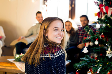 Young friends at decorated Christmas tree celebrating Christmas 
