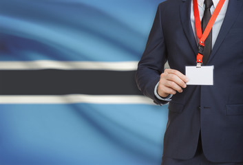 Businessman holding name card badge on a lanyard with a national flag on background - Botswana