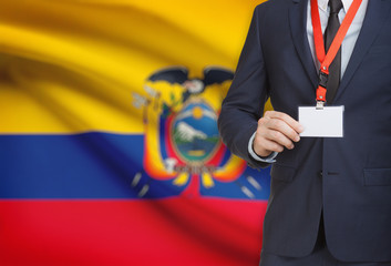 Businessman holding name card badge on a lanyard with a national flag on background - Ecuador