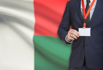 Businessman holding name card badge on a lanyard with a national flag on background - Madagascar