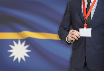 Businessman holding name card badge on a lanyard with a national flag on background - Nauru