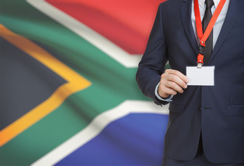 Businessman holding name card badge on a lanyard with a national flag on background - South Africa