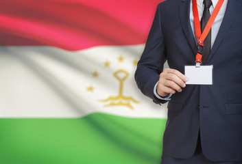 Businessman holding name card badge on a lanyard with a national flag on background - Tajikistan