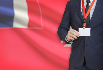 Businessman holding name card badge on a lanyard with a national flag on background - Wallis and...