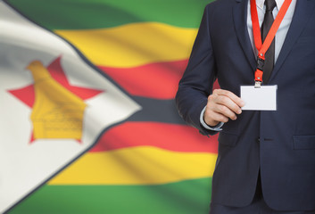 Businessman holding name card badge on a lanyard with a national flag on background - Zimbabwe
