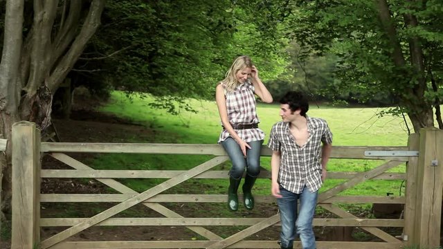 Young couple sitting on gate and walking off hand in hand