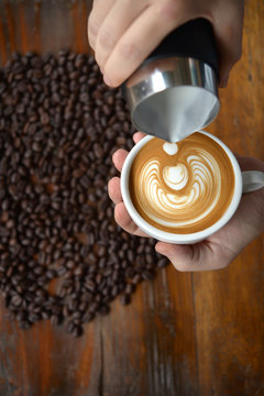 cup of coffee latte art making by barista on old wooden backgrou