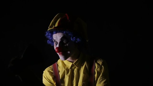 Terrifying clown with an axe frightening you. HD.