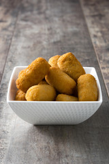 Traditional fried Spanish croquetas (croquettes) on wooden background
