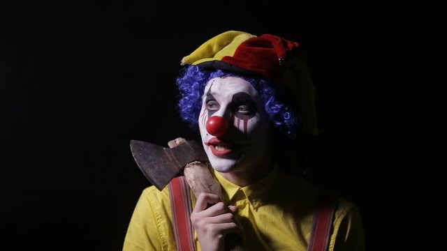 Terrifying clown with an axe frightening you. HD.