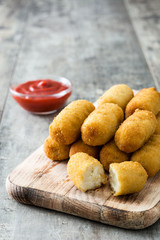 Traditional fried Spanish croquetas (croquettes) with ketchup on wooden background
