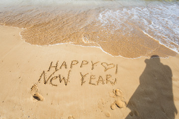 Happy New Year text on the sea beach.