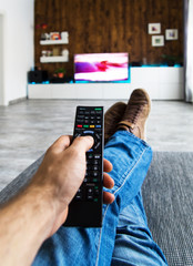 Zappen / Fernsehen auf der Couch mit Fernbedienung in der Hand
