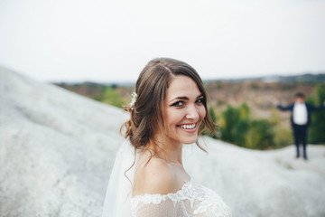 beautiful bride in a white dress stands outdoors