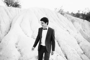 handsome and young groom in a suit walking outdoors