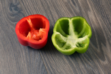 cut red and green bell peppers on wooden background