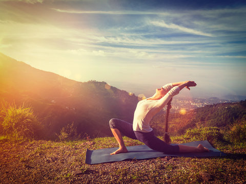 Sporty fit woman practices yoga Anjaneyasana in mountains