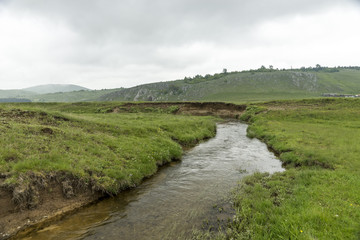 Fototapeta na wymiar Stream on a meadow in the mountains