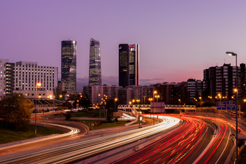 Fototapeta na wymiar Atardecer de Madrid con los rascacielos y las luces de la carretera
