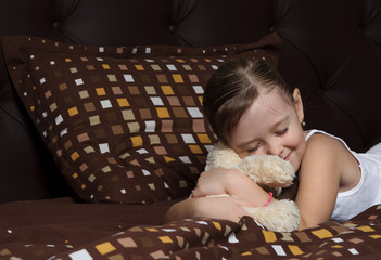 girl with soft toy sleeping in bed
