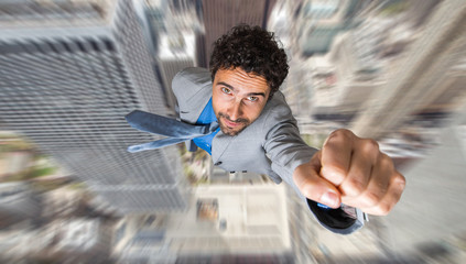 Businessman superhero flying above a city - obrazy, fototapety, plakaty