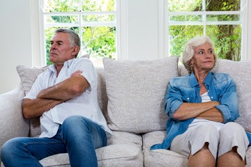 Annoyed senior couple looking away while sitting on sofa