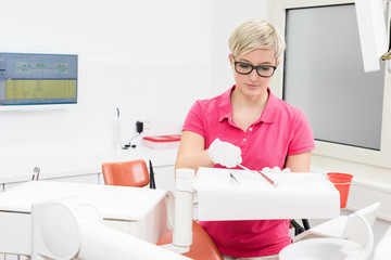 Junge Zahnarzthelferin bereitet Behandlungsraum vor
