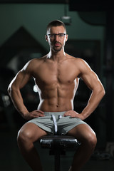 Fototapeta na wymiar Attractive Young Geek Resting In Gym Afther Exercise