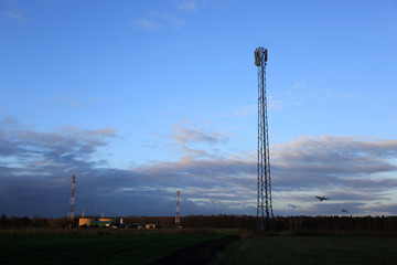 Anteny, maszty z antenami satelitarnymi na polach o zachodzie słońca.
