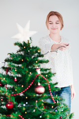Young girl decorating Christmas tree with lights