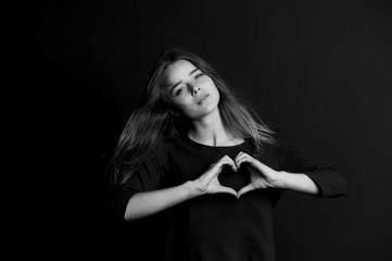 Beautiful girl makes a heart gesture with your fingers. BW