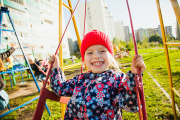 Cute happy little girl on playground enjoying swing. Sunny day, beautiful smile