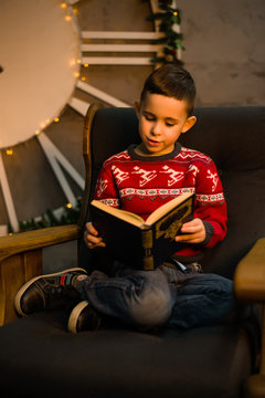 Boy sitting on chair and reading a book