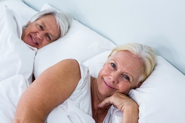 Portrait of smiling senior couple sleeping on bed 