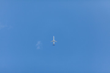Silhouette of an air-plane in the blue sky seen from below