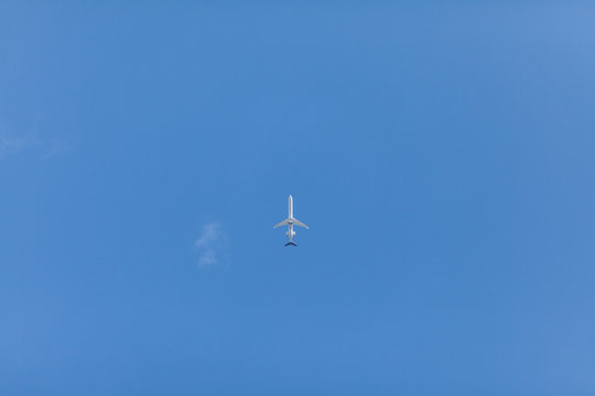 Silhouette of an air-plane in the blue sky seen from below