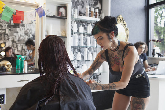 Female hair dresser cutting customer's hair in salon