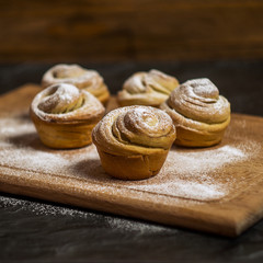 Homemade pastries cruffins, muffin with sugar powder, on wooden desk and dark background, selective focuse, square