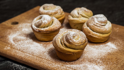 Homemade pastries cruffins, muffin with sugar powder, on wooden desk and dark background, selective focuse