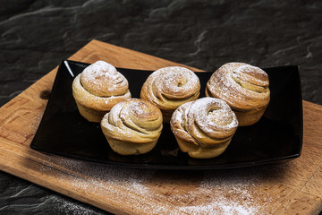 Homemade pastries cruffins, muffin with sugar powder, on wooden desk and dark background, selective focuse