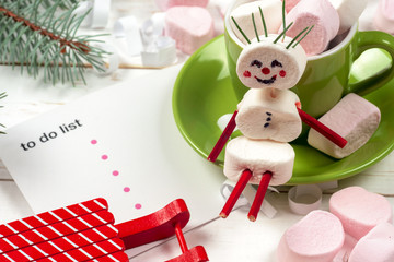 Christmas card with fun marshmallow snowman in green cup, tree