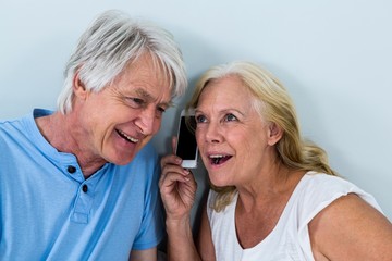Retired couple listening to music through smartphone 