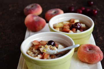 Delicious fragrant oatmeal with pieces of fresh fruit in a ceramic bowl. Sweet tasty breakfast. Idea for a healthy diet. Selective focus.