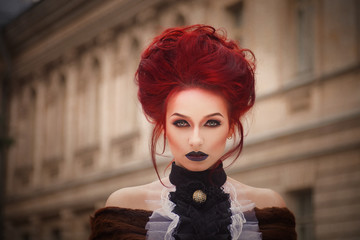 sexy woman with gothic makeup and red hair against old castle