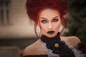 sexy woman with gothic makeup and red hair against old castle