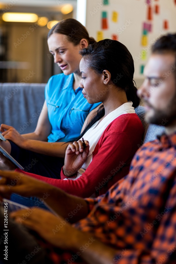 Aufkleber colleagues using digital tablet and laptop while sitting on sofa