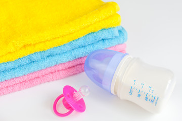 baby bottle with milk and towel on white background