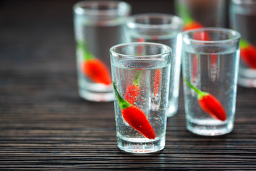 cold vodka with hot chili peppers , selective focus