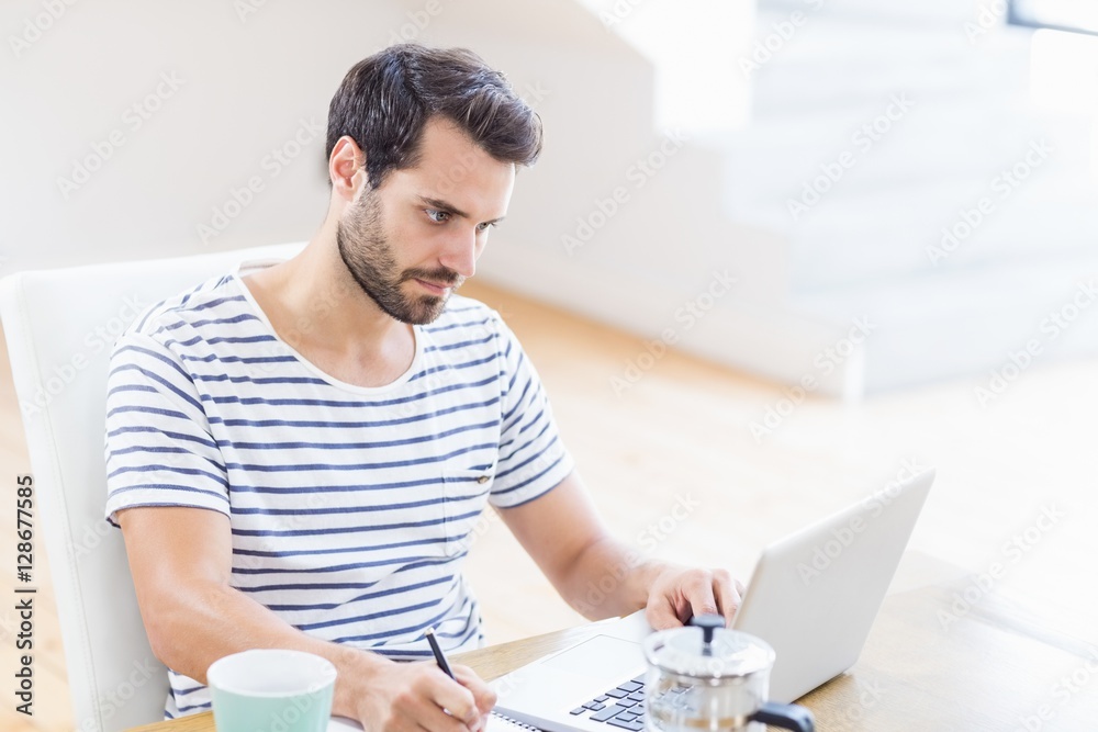 Poster man writing note using laptop