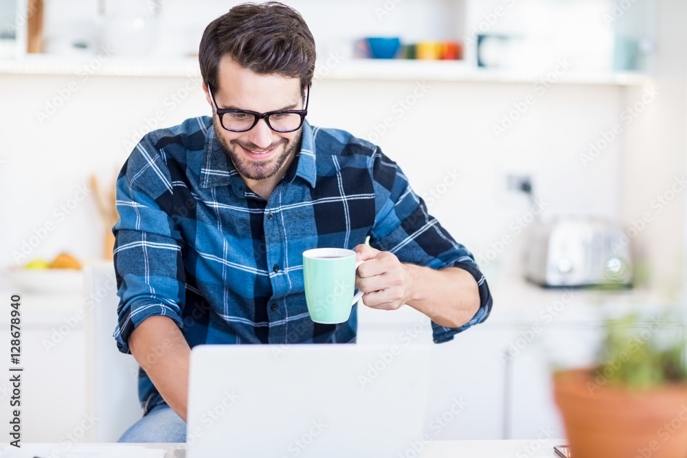 Poster man using laptop while having coffee